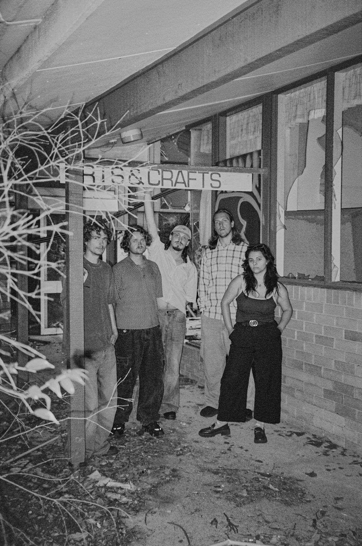 Aodhan under an old Arts & Crafts sign outside an abandoned building at night, black and white