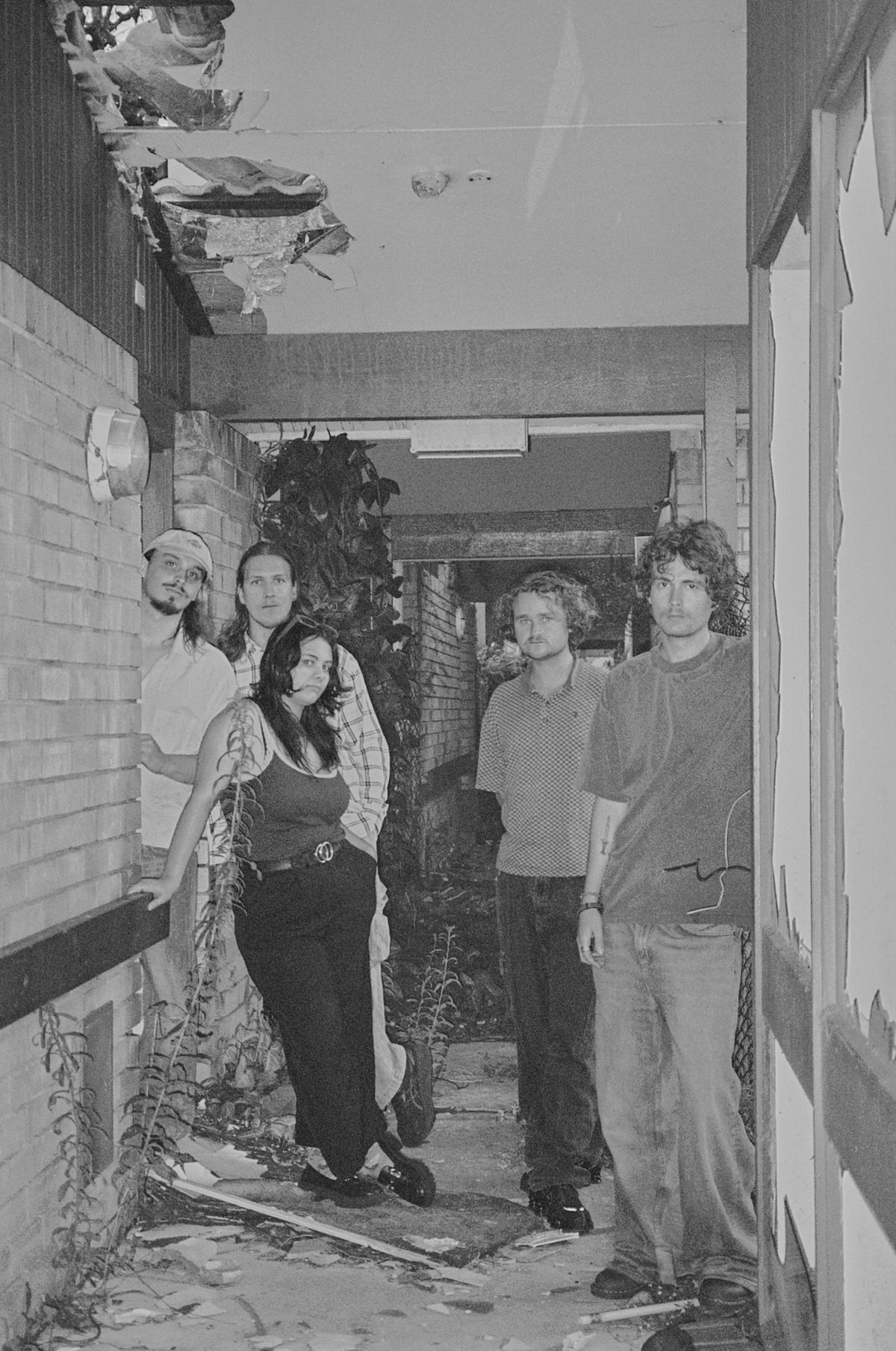 Aodhan standing in the corridor of a derelict brick building, black and white
