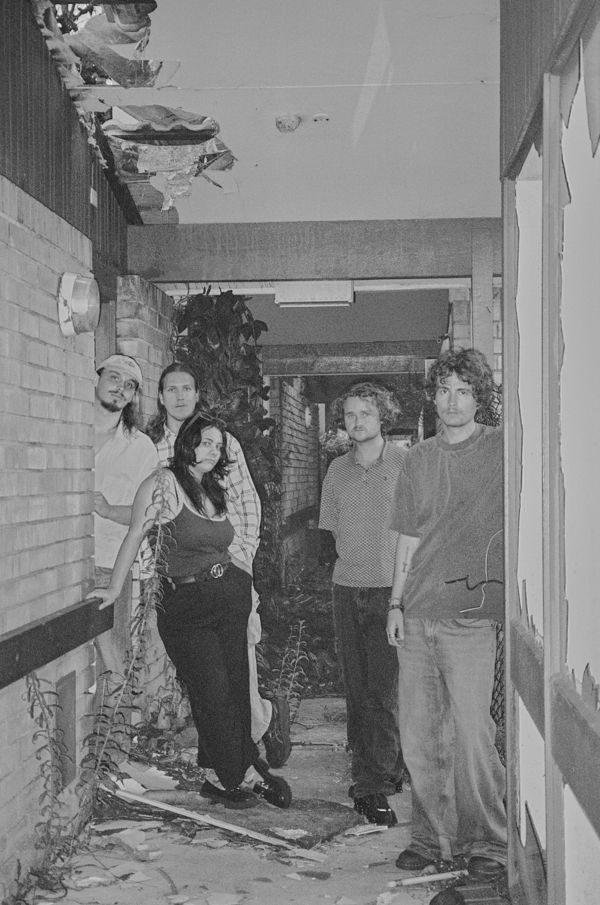 Aodhan standing in the corridor of a derelict brick building, black and white