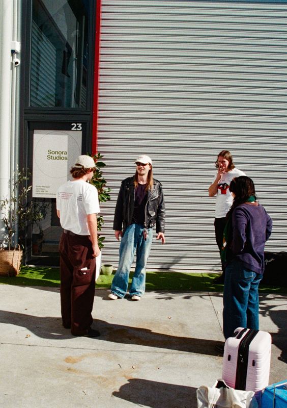 Aodhan in the studio: four people standing outside the studio roller door in the sun