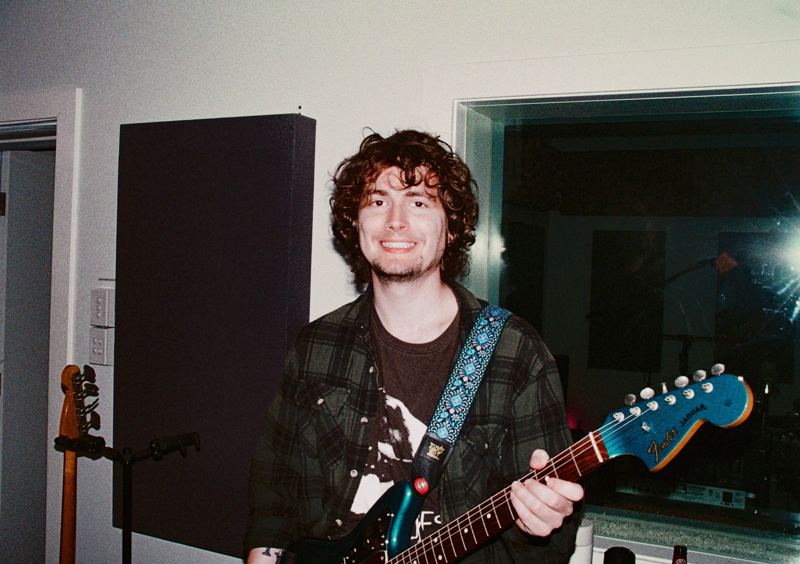Aodhan in the studio: guitarist smiling with a teal electric guitar