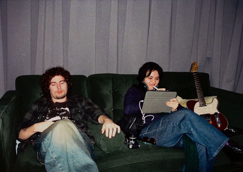 Aodhan in the studio: two people on the studio couch, one sketching on a tablet