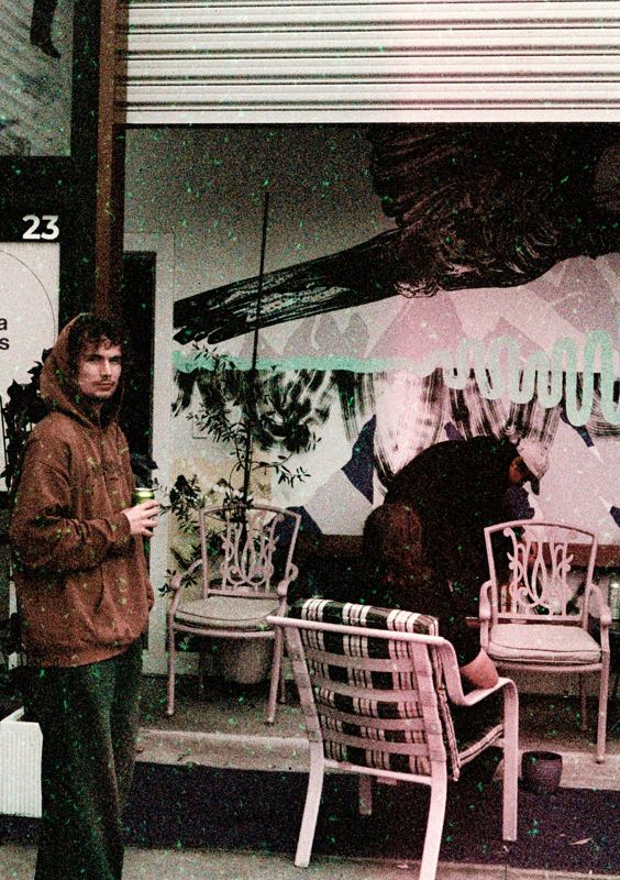 Aodhan in the studio: standing beside a mural and garden chairs outside the studio