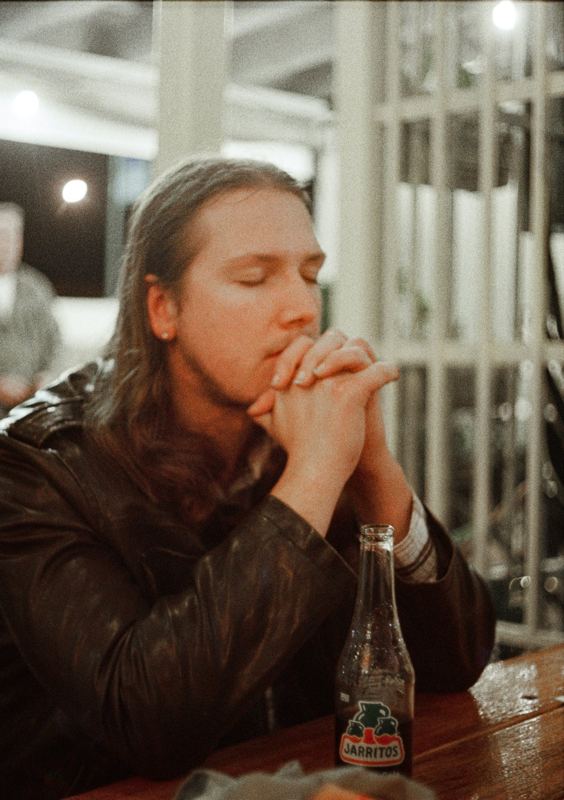 Aodhan in the studio: sitting at a table with hands clasped, deep in thought