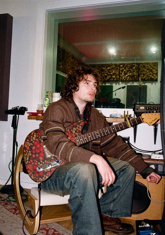 Aodhan in the studio: guitarist seated with a red paisley guitar
