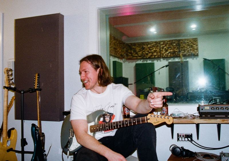Aodhan in the studio: guitarist laughing and pointing, silver guitar in hand