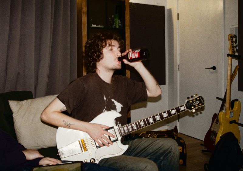 Aodhan in the studio: guitarist taking a drink mid-session with a white guitar