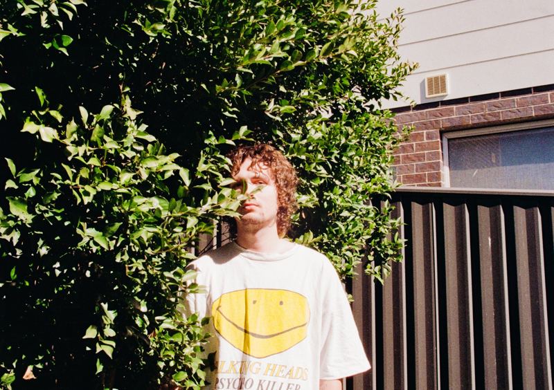 Aodhan in the studio: standing in front of a sunlit hedge