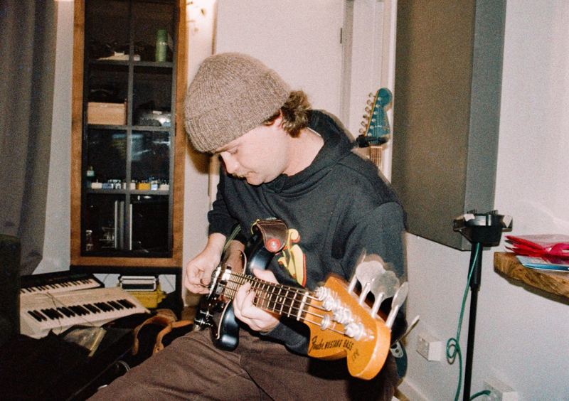 Aodhan in the studio: bassist in a beanie playing a bass guitar